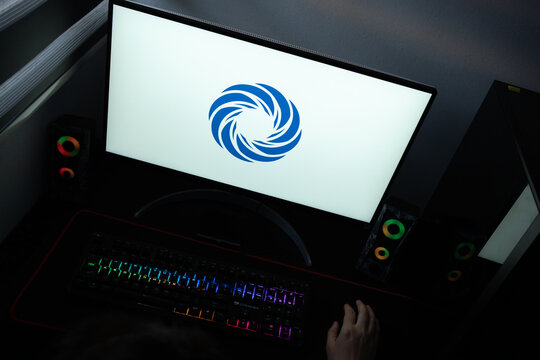 Punta Arenas, Chile &ndash; June 12, 2026: The official blue swirl CloudLinux logo displayed on a computer screen in a dark room workspace setup with an RGB backlit keyboard