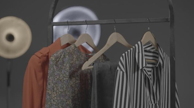 Clothes of various styles hang neatly on wooden hangers on a shelf inside the boutique display window of a modern clothing store.