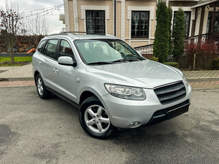 Fototapeta premium Silver SUV parked near a building with trees and a stone path, showing the vehicle's design and setting