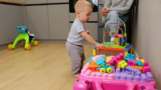 Toddler playing with colorfull block at table play in indoor room child explores toy and practices coordination with block supervised by mother and learning