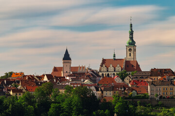 Obraz premium Historic center of Tabor featuring the Church of the Transfiguration above traditional rooftops under soft morning sky in South Bohemia, Czech Republic.