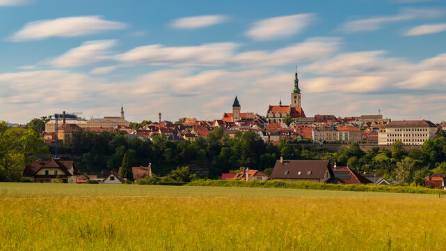 Historic town of Tabor with the Church of the Transfiguration rising above green countryside under moving clouds in South Bohemia, Czech Republic. Long exposure landscape scene.
