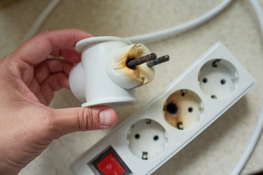 Burned power strip and damaged electrical plug caused by overheating, short circuit, overload and fire hazard in home.