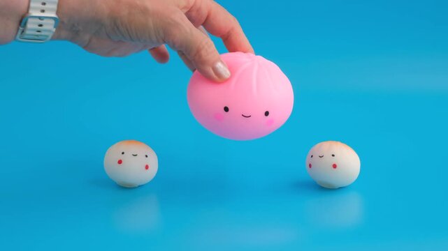 Three soft anti-stress toys in the shape of a dumpling with a happy face on a blue background