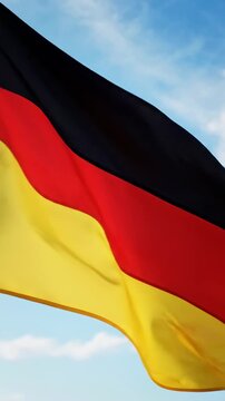 German flag waving in closeup with black red yellow fabric against blue cloudy sky in vertical video frame, patriotic european identity concept, Day of German Unity