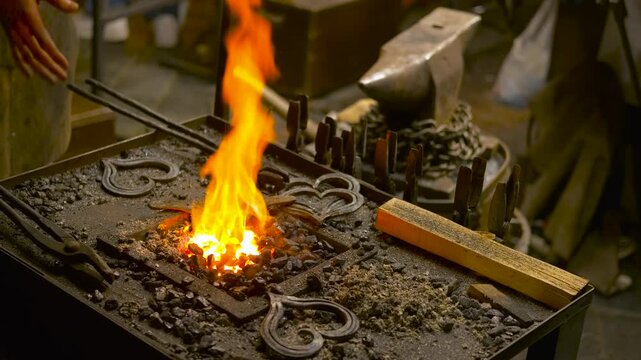 Blacksmith forging metal hearts in a workshop. Roaring fire burning in a blacksmith's forge with heart-shaped metal pieces and tools, showcasing traditional metalworking techniques in a dimly lit