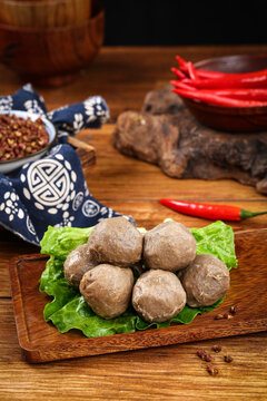 Traditional Chinese Chaoshan Beef Balls on Wooden Board with Red Chili Peppers and Lettuce
