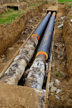 Old district heating pipes with outdated insulation being replaced by new insulated pipes in excavation trench, utility renovation and infrastructure modernization