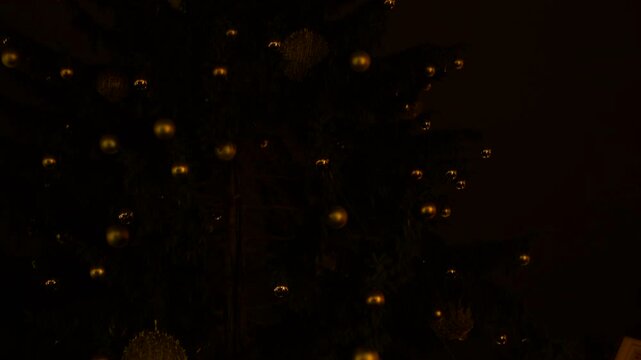 Golden christmas tree lights twinkling at night. Huge outdoor christmas tree illuminating the dark night with thousands of warm golden lights and festive ornaments, creating a magical atmospheren