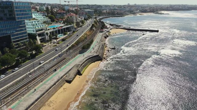 Aerial drone view over a beach breakwater and Marginal coastal road in Cascais Portugal