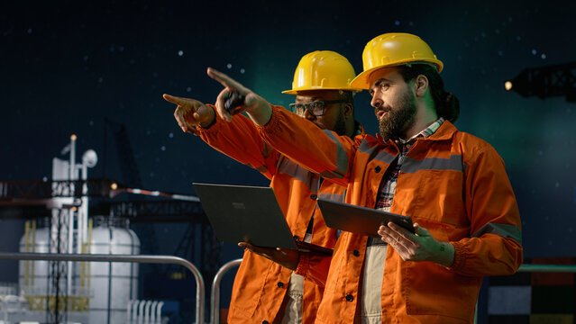 Analyzing oil crisis logistics, laptop and drilling barge engineering team men under green aurora borealis, Working together, maritime blockade strategy and offshore rig colleagues, camera A.