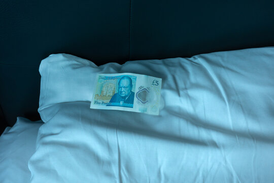 Five pound note on hotel pillow representing travel spending, hospitality, comfort, financial exchange and tourism economy concept in modern lifestyle.