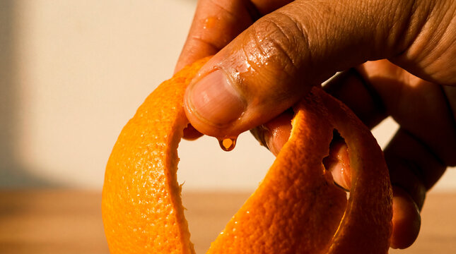 Precise hand peels orange rind in warm macro study of citrus texture