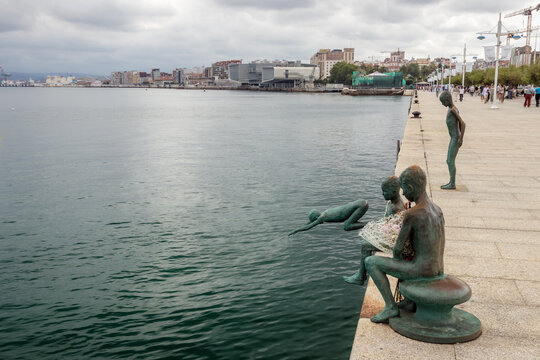 Santander, Spain - August 01, 2024: Los Raqueros sculptures on the promenade in Santander, Cantabria, Spain, with the Bot&iacute;n Centre and the city skyline in the background, on a cloudy summer day.