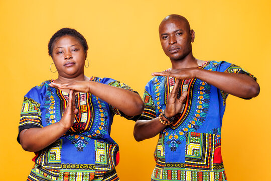 Confident man and woman showing timeout gesture with hands and looking at camera, serious African American couple indicating stop signal, asking to take break studio portrait.