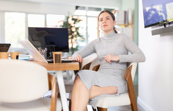 Beautiful female employee poses on armchair in a modern office
