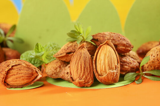 Fresh Almonds in Shells with Green Leaves on Colorful Background - Natural Organic Nuts and Healthy Snack Food