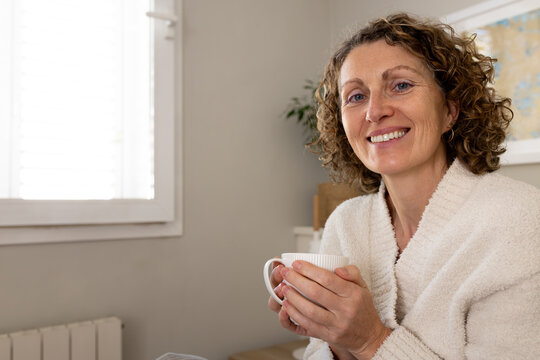 Smiling woman relaxing at home enjoying morning coffee