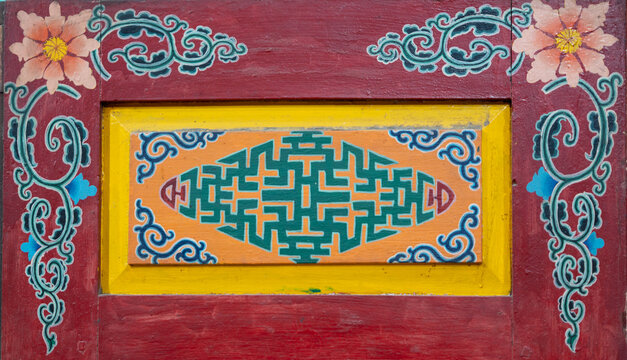 Traditional painted wooden panel with geometric pattern and floral corner decoration