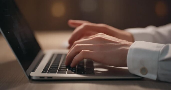 Professional person typing on laptop keyboard working remotely from home office desk setup.