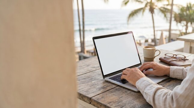Digital nomad working on laptop at beachside cafe, remote professional typing on computer with ocean view, freelance lifestyle concept