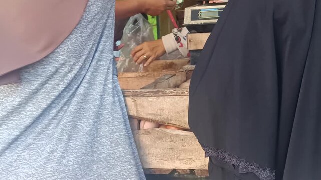 A close up view of fresh eggs in wooden crates at a vibrant market. A customer is seen purchasing eggs, highlighting a common grocery shopping scene.