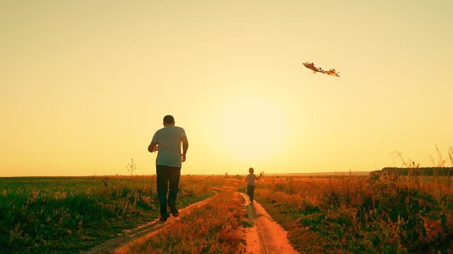 Family fun in park with child. Dad little son launch kite into sunny sky summer nature park . Family weekend, active games of son father. Family picnic in nature, joyful emotions. Parent raising child