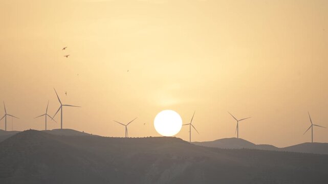 Wind turbines in mountainous region landscape in Taza, Morocco during dusk with setting sun, renewable energy for clean environment