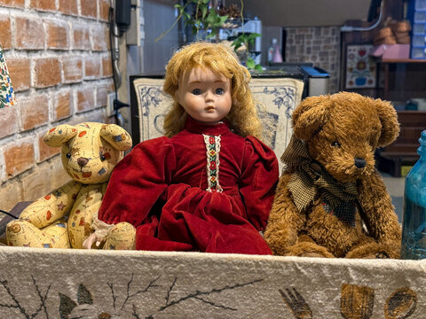 Vintage porcelain doll sitting between two teddy bears