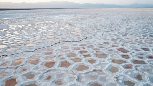 Salt flats display a unique geometric pattern of dried mineral crusts stretching across the vast desert landscape.