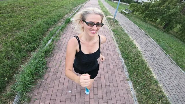 woman in athletic clothing jogging in park to promote healthy lifestyle. Fit female runner exercising on a rural road to demonstrate a healthy life. running vigorously outdoors cardiovascular workout.