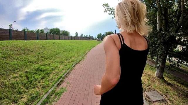SLOW MOTION side view of a healthy woman in sportswear running in the park at sunset. Cardio jogging workout girl training outdoor. Healthy life concept.