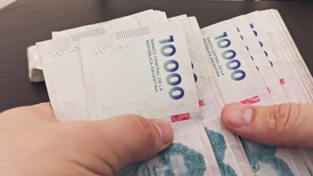 Person counting a stack of colombian pesos bills