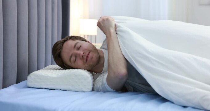 Man lying on bed with orthopedic pillow at home