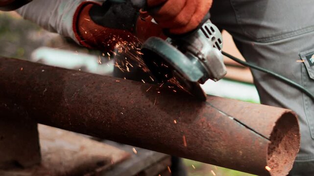 Closeup of professional craftsman using angle grinder on metal pipe outdoors. Dynamic sparks and industrial equipment symbolize skilled labor, infrastructure maintenance and technical expertise.