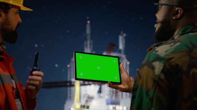 Green screen tablet, enforcing blockade and military man on drilling rig with walkie talkie with green screen tablet mockup.