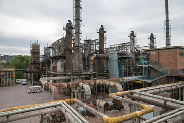 Fototapeta premium Aging industrial factory complex with rusted pipes and smokestacks