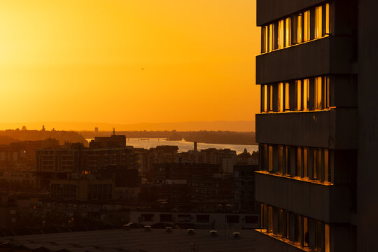 Golden sunset over modern city skyline with river and residential buildings