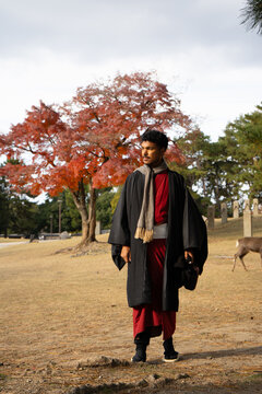 Traveler in traditional attire walking through Nara Park in autumn