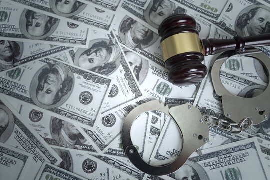 Judge gavel and handcuffs on US dollar banknotes symbolizing financial crime