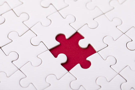 White jigsaw puzzle with red missing piece gap close up