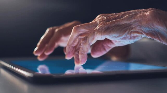 Elderly hand gently swiping across glowing tablet screen with illuminated wrinkles closeup technology use