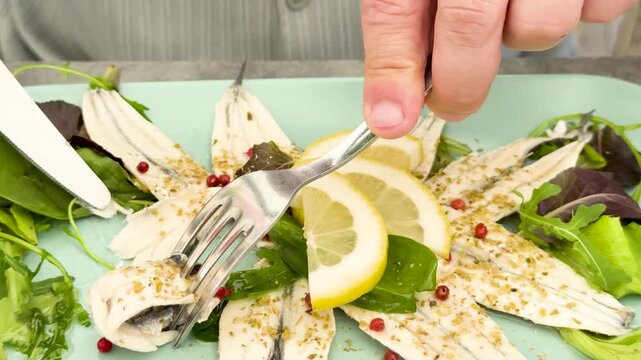 Close Up of Person Eating Marinated Anchovies with Lemon and Greens