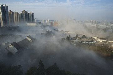 Urban demolition site with dust cloud and high rise buildings © NguyenMinh