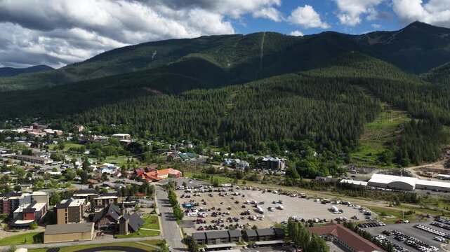 Aerial of small town and forest near Kellogg Idaho with residential buildings parking lots and dense forest under cloudy skies