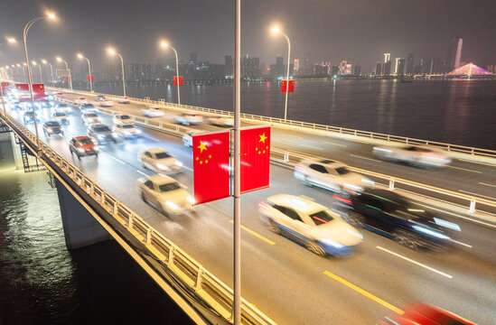 Night traffic on Yangtze River bridge with Chinese flags in Wuhan, China