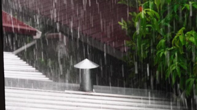 Clear raindrops after a summer rain fall on the roof of a house, a beautiful natural backdrop with raindrops on tropical leaves.