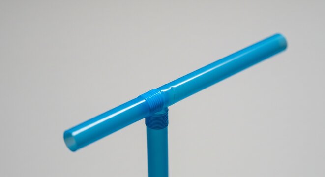 Vibrant blue plastic T shaped pipe connector bathed in soft diffused light creating gentle reflections. AI Generated