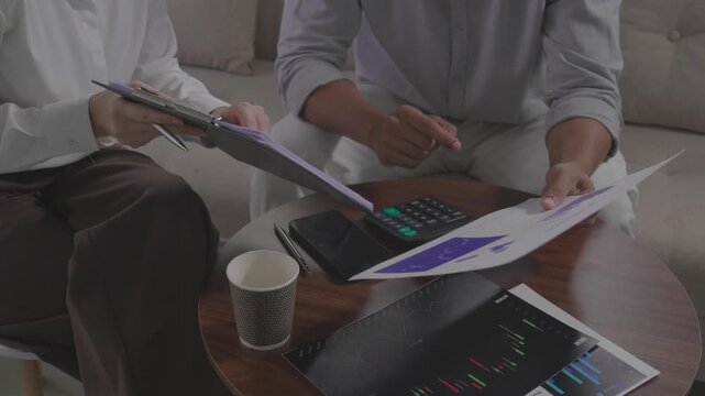  Client pointing at document during business contract signing meeting.Close up of hands reviewing financial insurance contract agreement details.