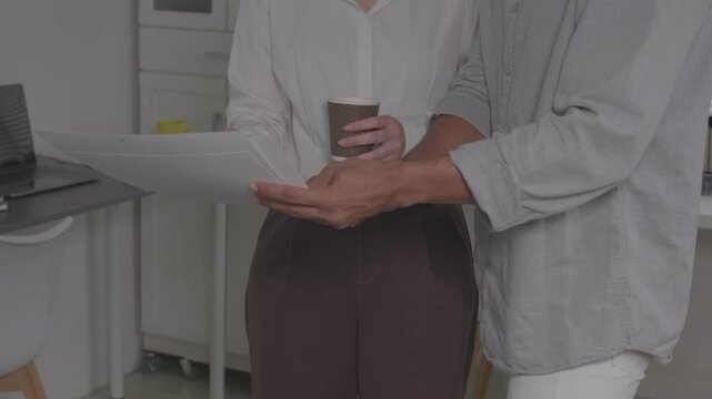  Client pointing at document during business contract signing meeting.Close up of hands reviewing financial insurance contract agreement details.